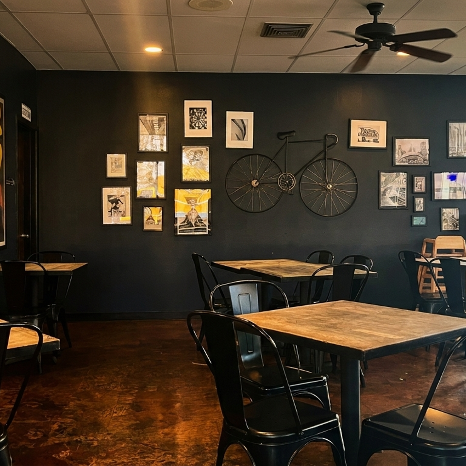 A restaurant dining room with dark walls, wooden tables, black chairs, and eclectic wall art.